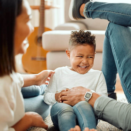 Happy young child laughing with parents, illustrating giving choices with love instead of threats.