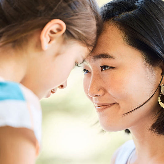 Mother and daughter touching foreheads and smiling, representing connection and understanding behind defiant behavior