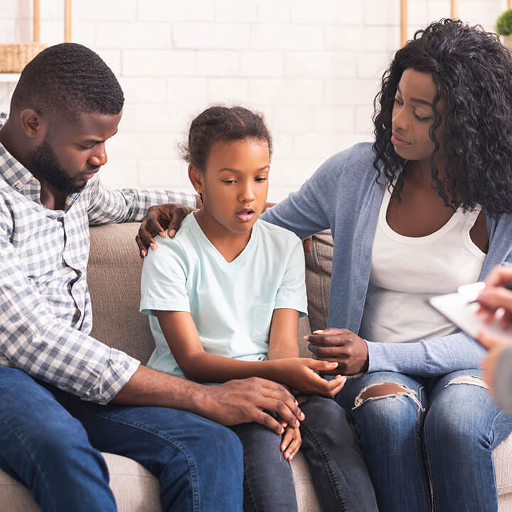 Parents listening with care to their daughter, modeling calm and supportive communication during a serious conversation