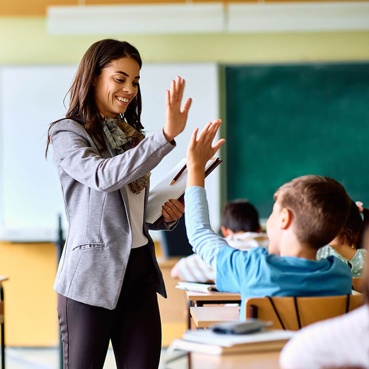 Teacher smiling and high-fiving a student in class, demonstrating empathy, respect, and connection central to building strong relationships with Love and Logic.