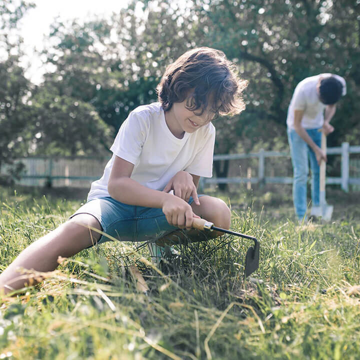 Child helping with summer yard work while a parent models responsibility, reflecting Love and Logic’s approach to using chores to build school-year success