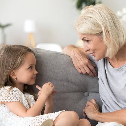grandmother calmly talking with granddaughter while helping her solve a problem