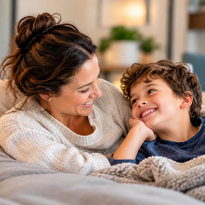 Mother and young son sharing a warm, affectionate moment together on the couch at home.