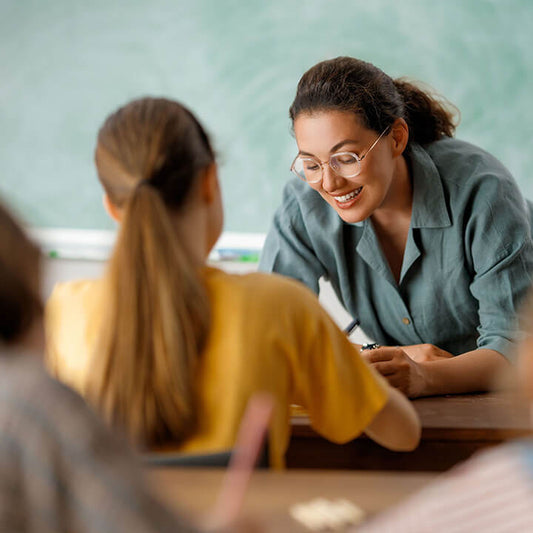 Teacher calmly giving instructions to attentive students, modeling empathy and clear classroom boundaries using Love and Logic techniques