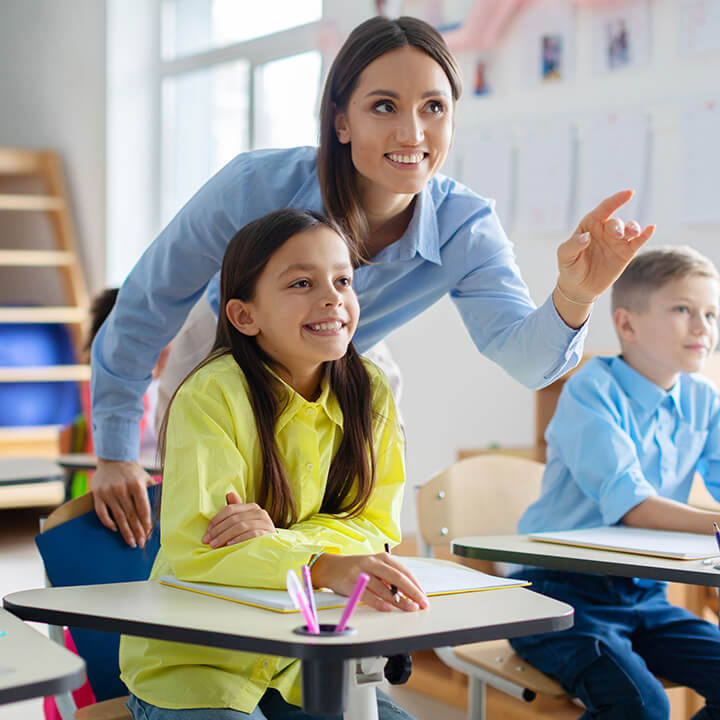Teacher pointing while guiding attentive students during a classroom lesson on listening and participation