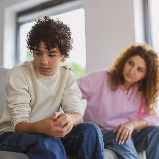 Parent sitting calmly beside a thoughtful child after a mistake, modeling empathy and guidance instead of anger.