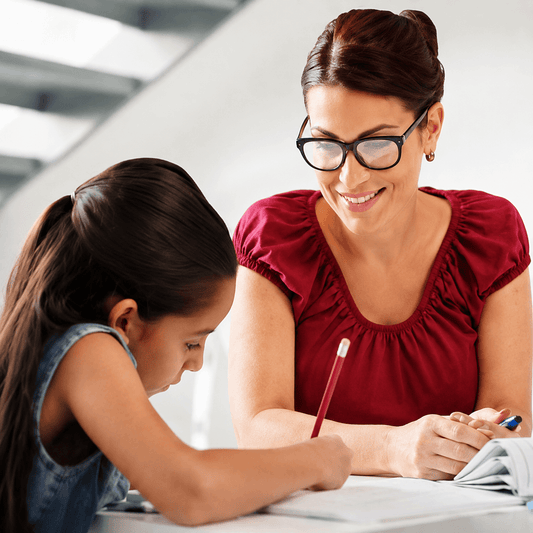 Parent helping a child with schoolwork while giving her space to learn from mistakes.