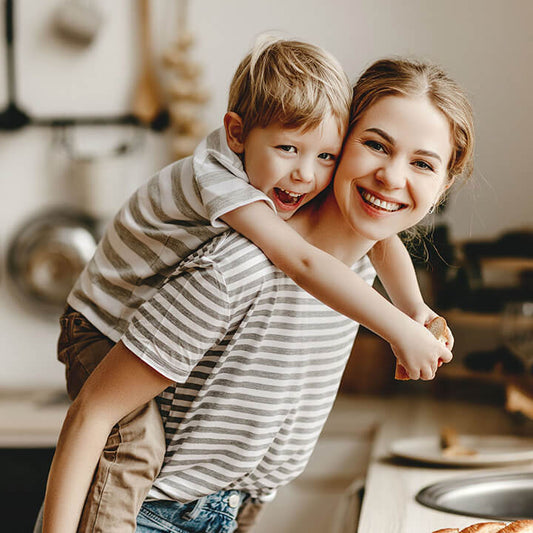 Smiling parent giving a child a piggyback ride in the kitchen, capturing the warmth and connection that come from positive feelings in parenting.