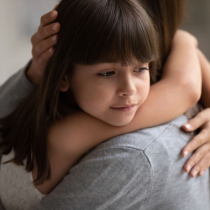 A child receiving a calm, supportive hug from an adult, reflecting safety, empathy, and emotional connection.