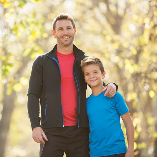 Smiling father with his arm around his son outdoors, representing the positive parent-child connection built through enforceable statements.