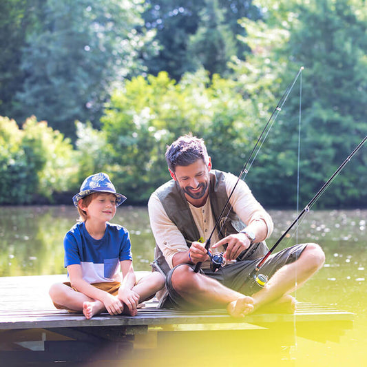 Father patiently teaching his son how to fish on a dock, showing love and connection through shared time together.